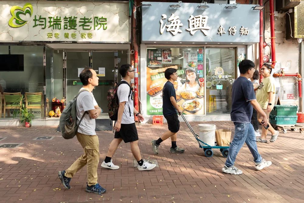 Researchers with a trolley walking past shops in San Hui
