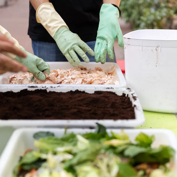 Gloved hands mixing food scraps and soil