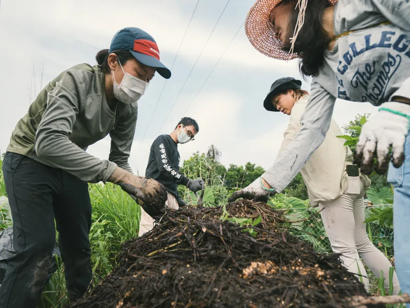 Participants turning a compost heap together on a farm